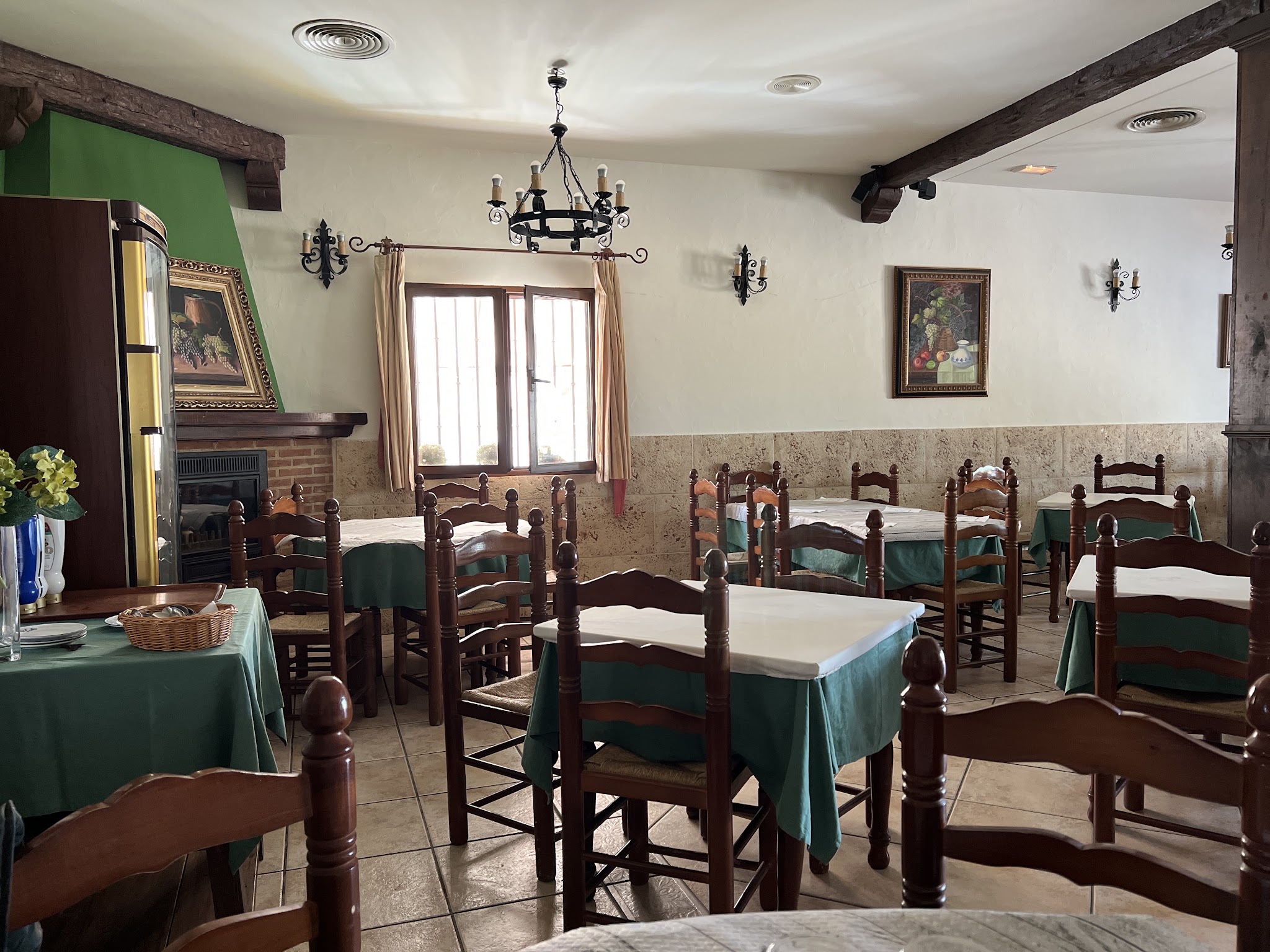 Restaurant dining room with wooden chairs, white tablecloths and green table coverings